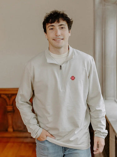 Male model wearing the smoke-colored Chi Phi Embroidered Luxe Quarter Zip with Symbol embroidery, standing by a window in a formal setting.