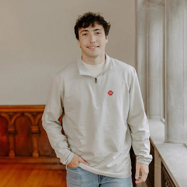 Male model wearing the smoke-colored Chi Phi Embroidered Luxe Quarter Zip with crest embroidery, standing by a window in a formal setting.