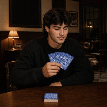 Fraternity brother holding custom Heritage Playing Cards during a poker game in a chapter house lounge.