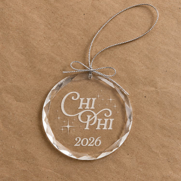 2026 Limited Edition clear glass holiday ornament featuring engraved fraternity design and silver hanging string