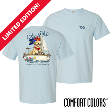 Light blue Comfort Colors t-shirt shown front and back; front features small Greek letters on the left chest, back displays a golden retriever sailing a boat with script text above and “Chasing Open Water” below.